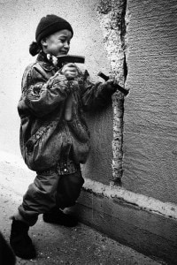 Foto di una bambina che tenta di rompere il muro dal lato di Berlino Est