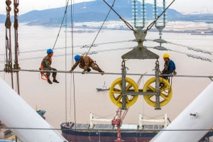 I lavoratori montano i cavi su una torre di trasmissione ad alta tensione da 500 kv il 22 ottobre 2018. Città di Zhoushan, Cina