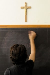 La foto scattata il 1 luglio 2010 mostra un insegnante che pulisce una lavagna sotto un crocifisso in un'aula di una scuola di Viterbo