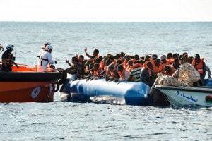 Migranti e rifugiati siedono su un gommone durante un'operazione di salvataggio della Topaz Responder, nave gestita dalla ONG "Moas" e dalla CRI con l'aiuto della guardia costiera libica, il 4 novembre 2016 al largo delle coste libiche