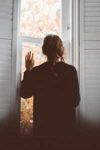 Una donna che saluta dalla finestra. Il distanziamento, sociale o fisico, è un'azione di controllo volta a fermare o rallentare la diffusione di una malattia contagiosa