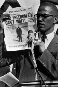 Malcolm X solleva un numero del quotidiano "Muhammad Speaks" durante una manifestazione a New York, 27 luglio 1963