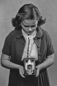 L'immagine ritrae una bambina mentre scatta una fotografia con la Kodak box Brownie, 1935 circa