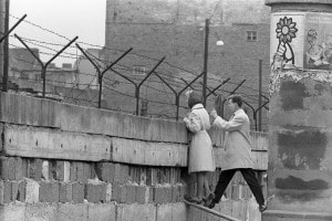 Una coppia affacciata in cima al muro che divideva Berlino Est da Berlino Ovest
