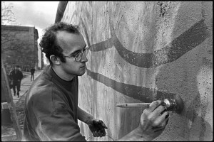 Keith Haring a Berlino nel 1986 mentre dipinge il Muro vicino al Checkpoint Charlie